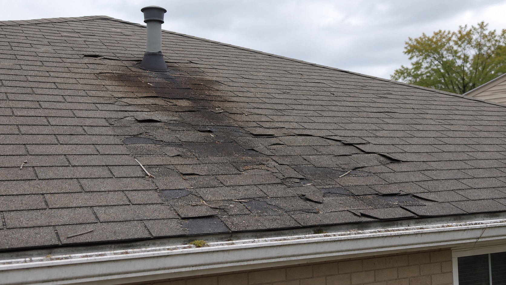 Before photo showing damaged asphalt shingles and roof staining